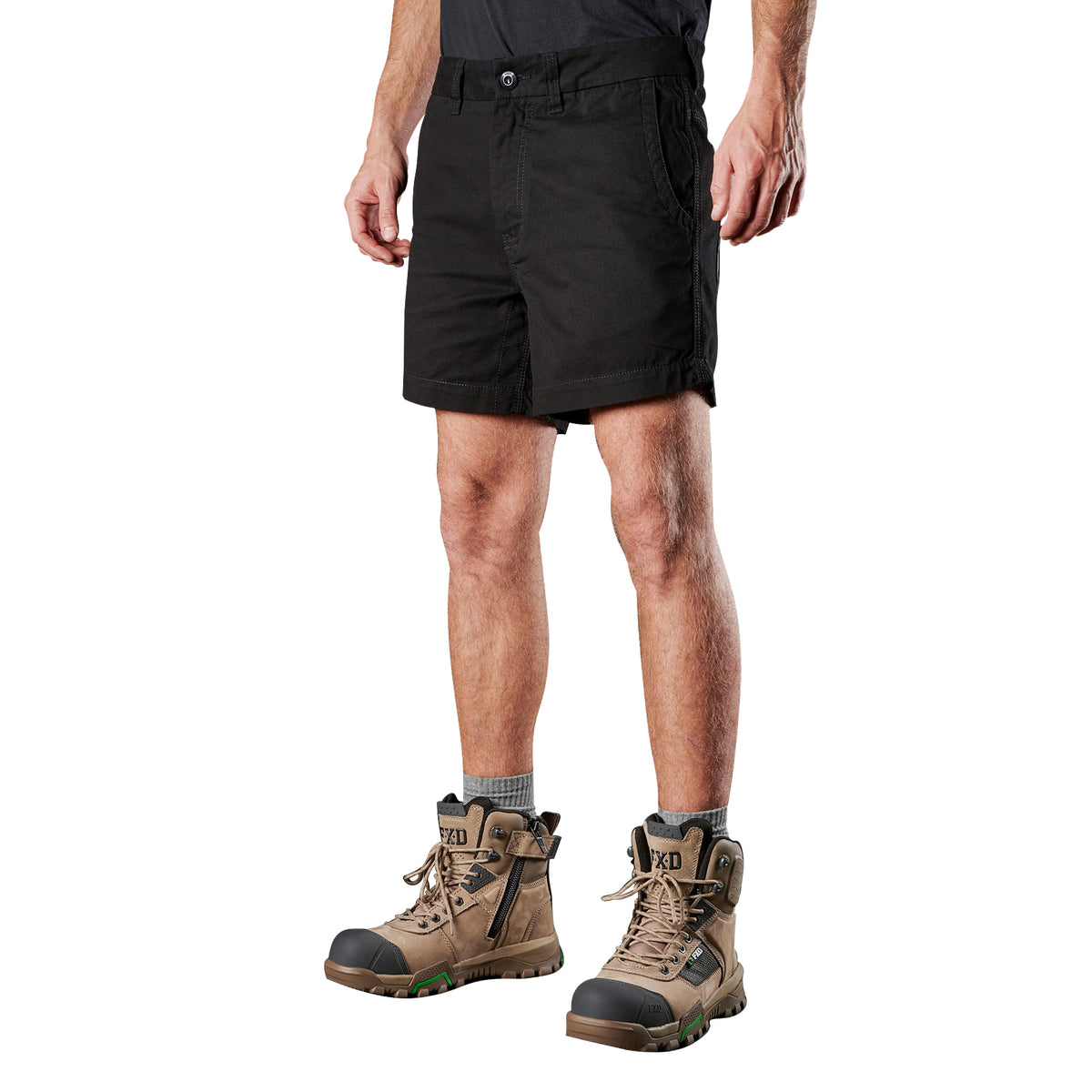 A man from the waist down wearing black FXD Men's WS-2 Work Shorts (FX01136005), grey socks, and stone FXD work boots against a solid white background.