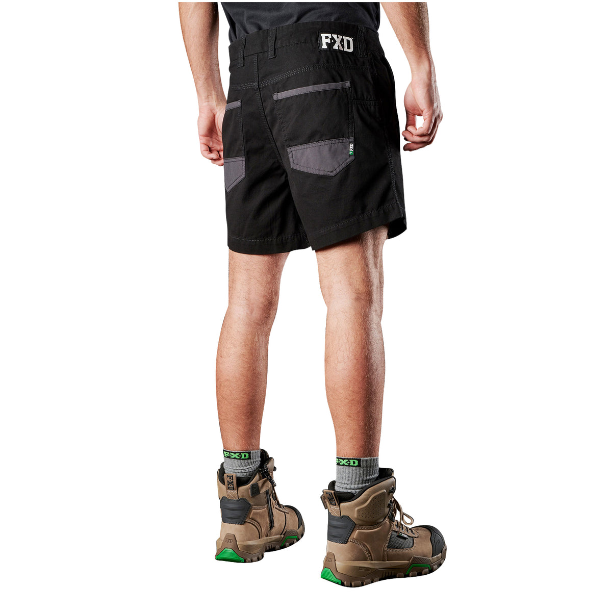A 3-4 back view of a man from the waist down wearing black FXD Men's WS-2 Work Shorts (FX01136005), grey socks, and stone FXD work boots against a solid white background.