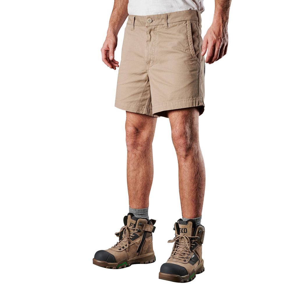 A 3-4 front view of a man modelling a pair of khaki FXD Men's WS-2 Work Shorts (FX01136005) paired with grey socks, and stone FXD work boots against a plain white background.