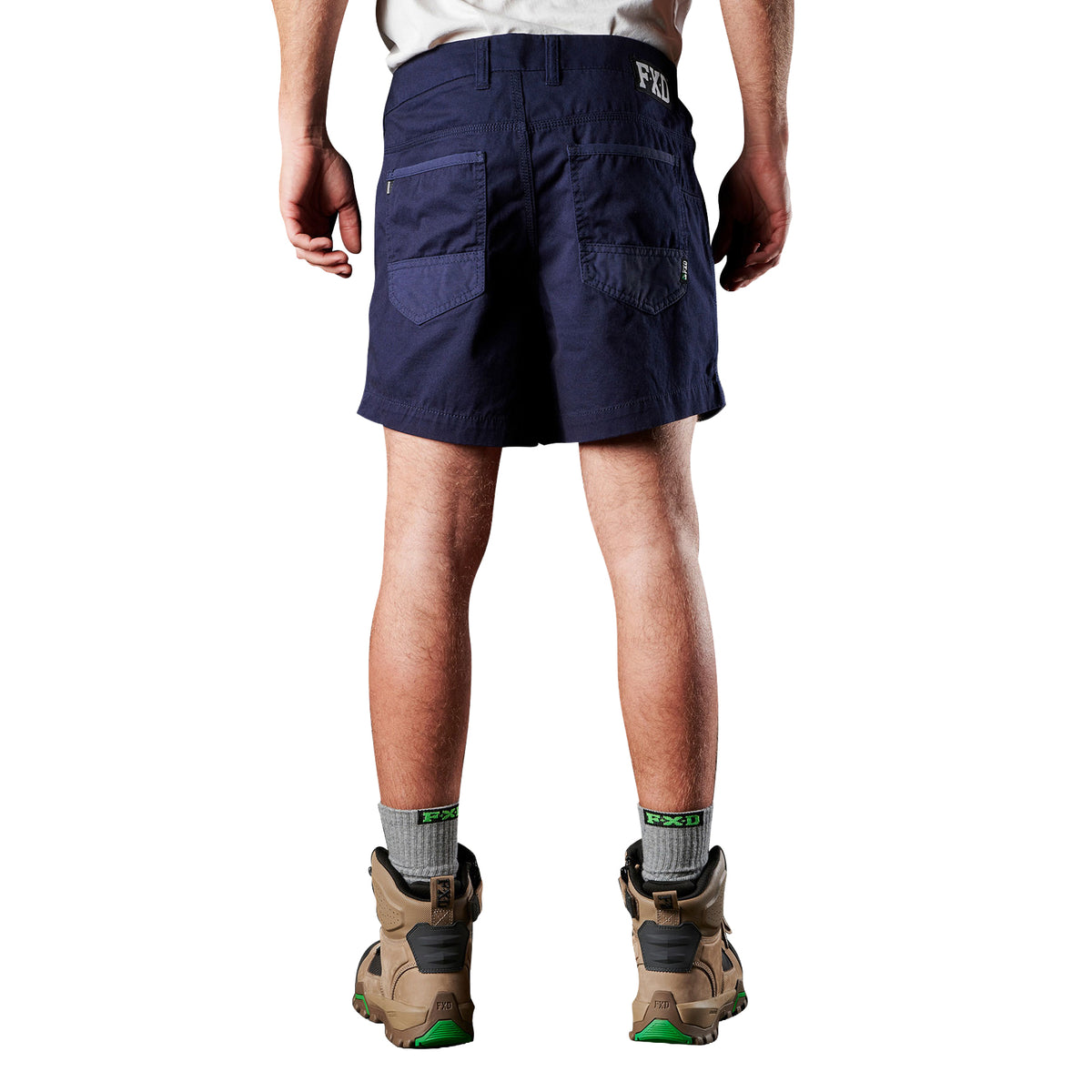 A man viewed from behind modelling navy blue FXD Men's WS-2 Work Shorts (FX01136005), paired with grey socks, and stone FXD work boots, shown from the waist down on a plain white background.
