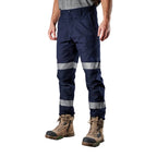 A model from the waist down, wearing navy blue FXD WP-3T Reflective Stretch Work Pants (FX01906010) with reflective silver stripes on the thighs and lower legs, paired with stone coloured work boots against a white background.
