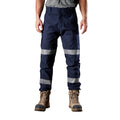A model from the waist down, wearing navy blue FXD WP-3T Reflective Stretch Work Pants (FX01906010) with reflective silver stripes on the thighs and lower legs, paired with stone coloured work boots against a white background.
