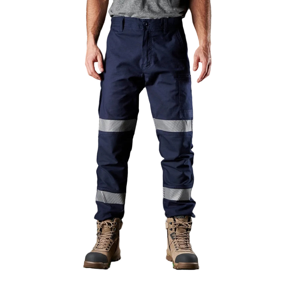 A model from the waist down, wearing navy blue FXD WP-3T Reflective Stretch Work Pants (FX01906010) with reflective silver stripes on the thighs and lower legs, paired with stone coloured work boots against a white background.