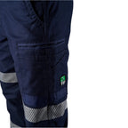 Close up pocket detail of the navy blue FXD WP-3T Reflective Stretch Work Pants (FX01906010) with reflective silver stripes on the thighs and lower legs, paired with stone coloured work boots against a white background.