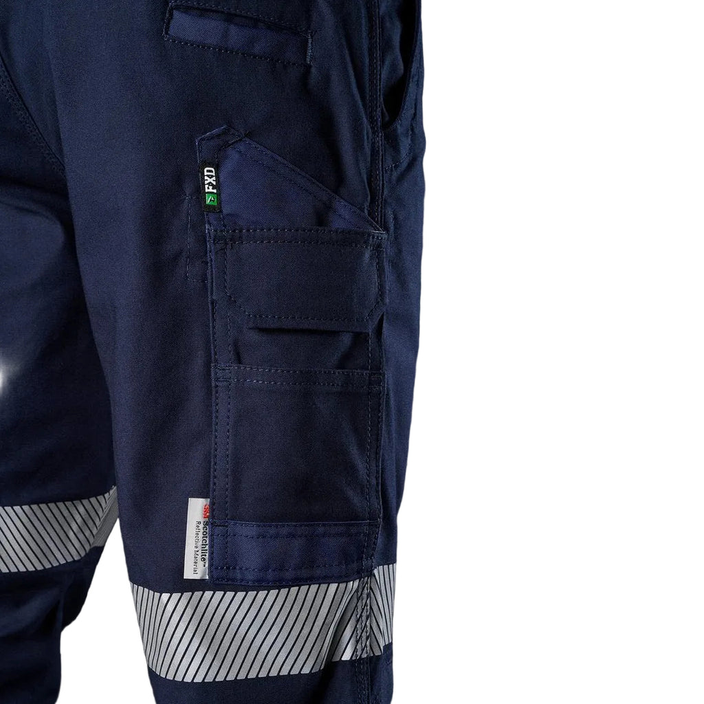 Close up thigh pocket detail of the navy blue FXD WP-3T Reflective Stretch Work Pants (FX01906010) with reflective silver stripes on the thighs and lower legs, paired with stone coloured work boots against a white background.