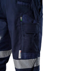 Close up thigh pocket detail of the navy blue FXD WP-3T Reflective Stretch Work Pants (FX01906010) with reflective silver stripes on the thighs and lower legs, paired with stone coloured work boots against a white background.