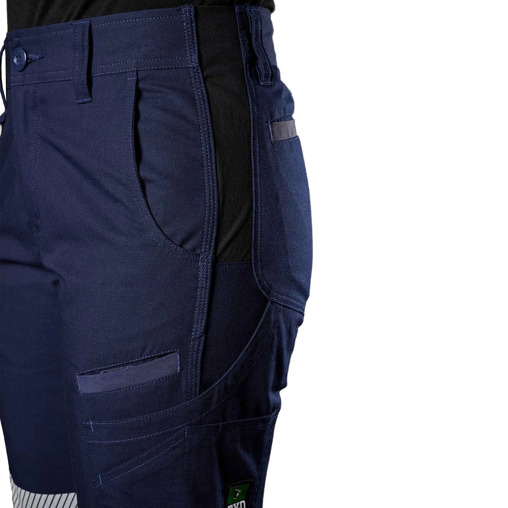 A close up view of the double weave flex hip panel of a pair of navy blue FXD Women's Cuffed Taped Work Pants (WP-8WT) paired with a black t-shirt against a plain white background.