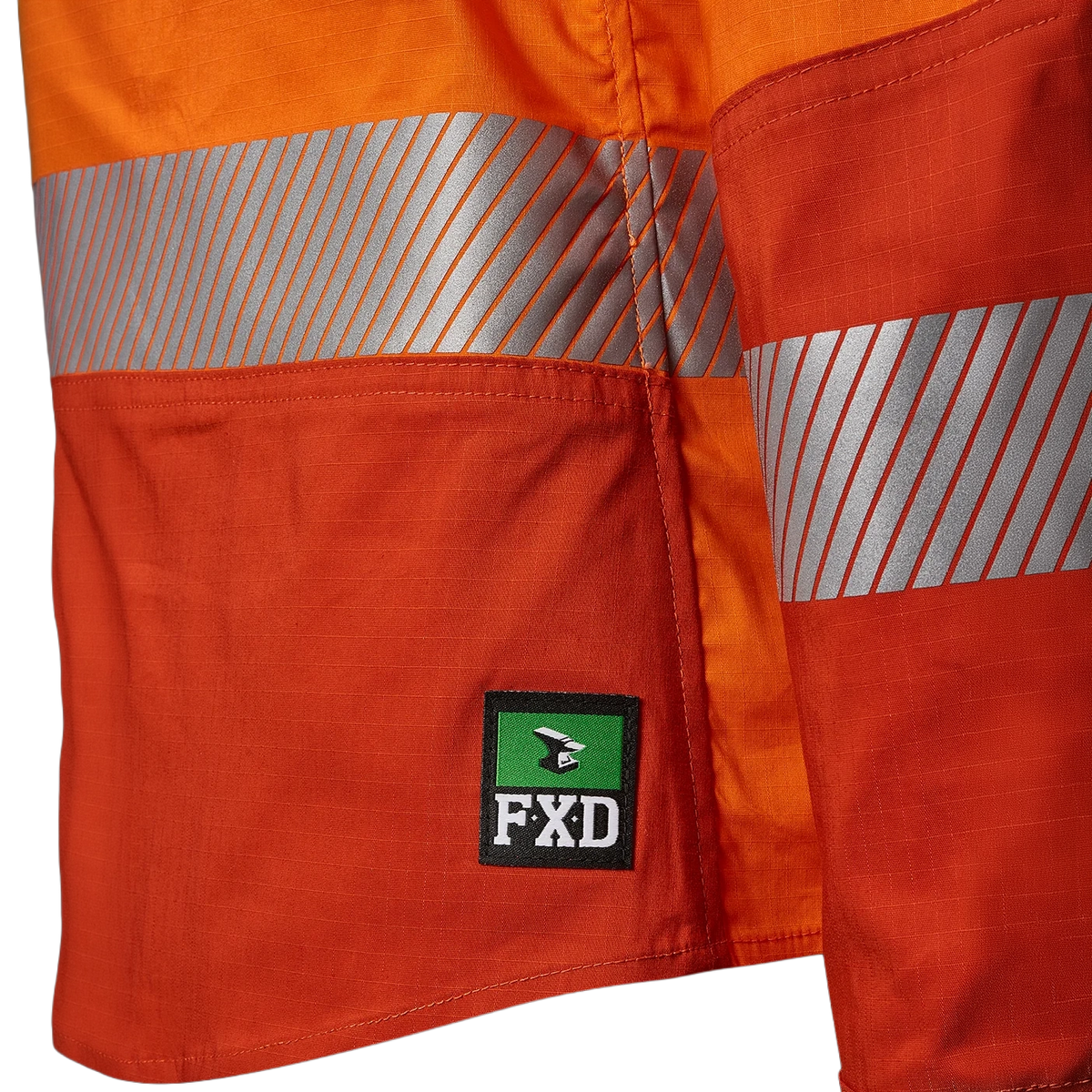 Close up detail of the FXD logo at the hem and tape on an orange FXD Women's LSH-2WT Hi Vis Taped Long Sleeve Work Shirt (FX12404100) on a white background.