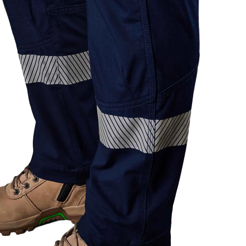 A close up view of the lower reflective bands on the navy blue FXD Women's Taped Cargo Work Pants (WP-7WT) paired stone coloured work boots, against a plain white background.