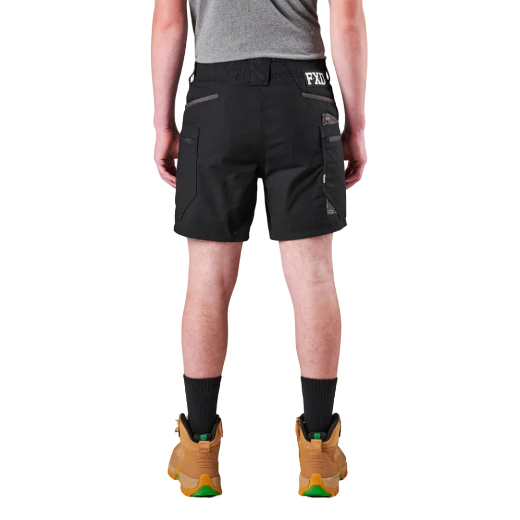 A model from the waist down wearing black FXD Men's WS-6 Work Shorts (FX02306021), black crew socks, and tan work boots against a plain white background.