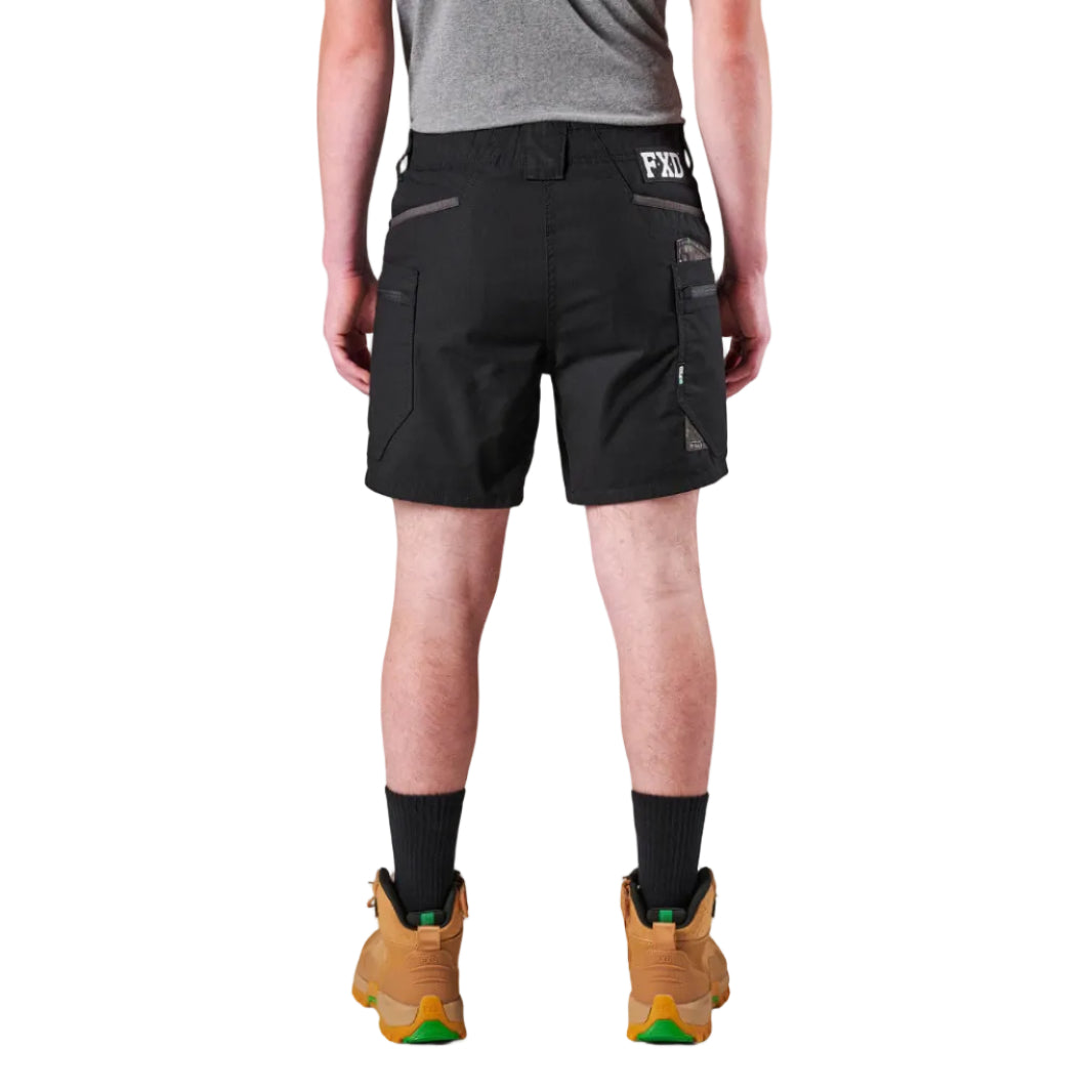 A model from the waist down wearing black FXD Men's WS-6 Work Shorts (FX02306021), black crew socks, and tan work boots against a plain white background.