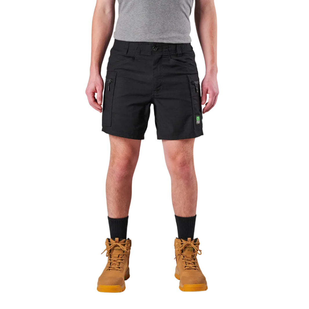 A model from the waist down wearing black FXD Men's WS-6 Work Shorts (FX02306021), black crew socks, and tan work boots against a plain white background.