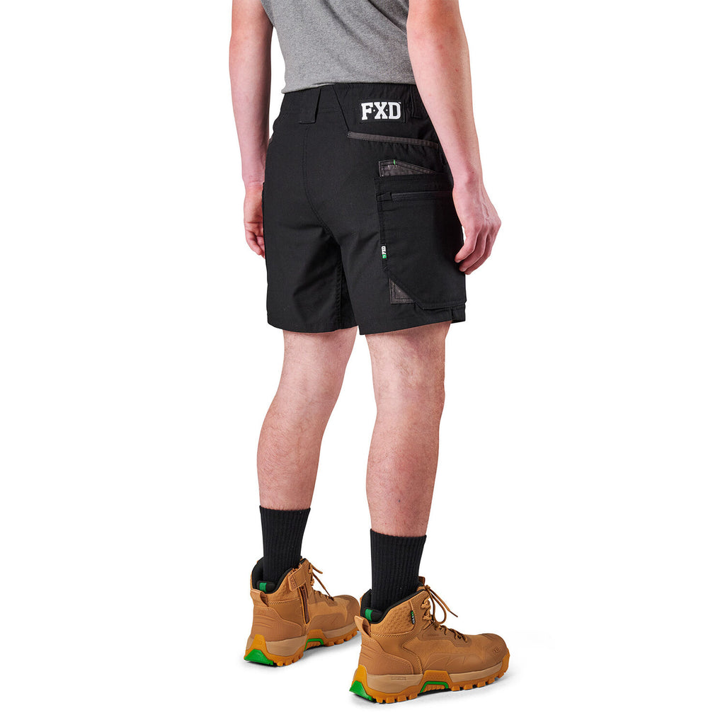 A model from the waist down wearing black FXD Men's WS-6 Work Shorts (FX02306021), black crew socks, and tan work boots against a plain white background.