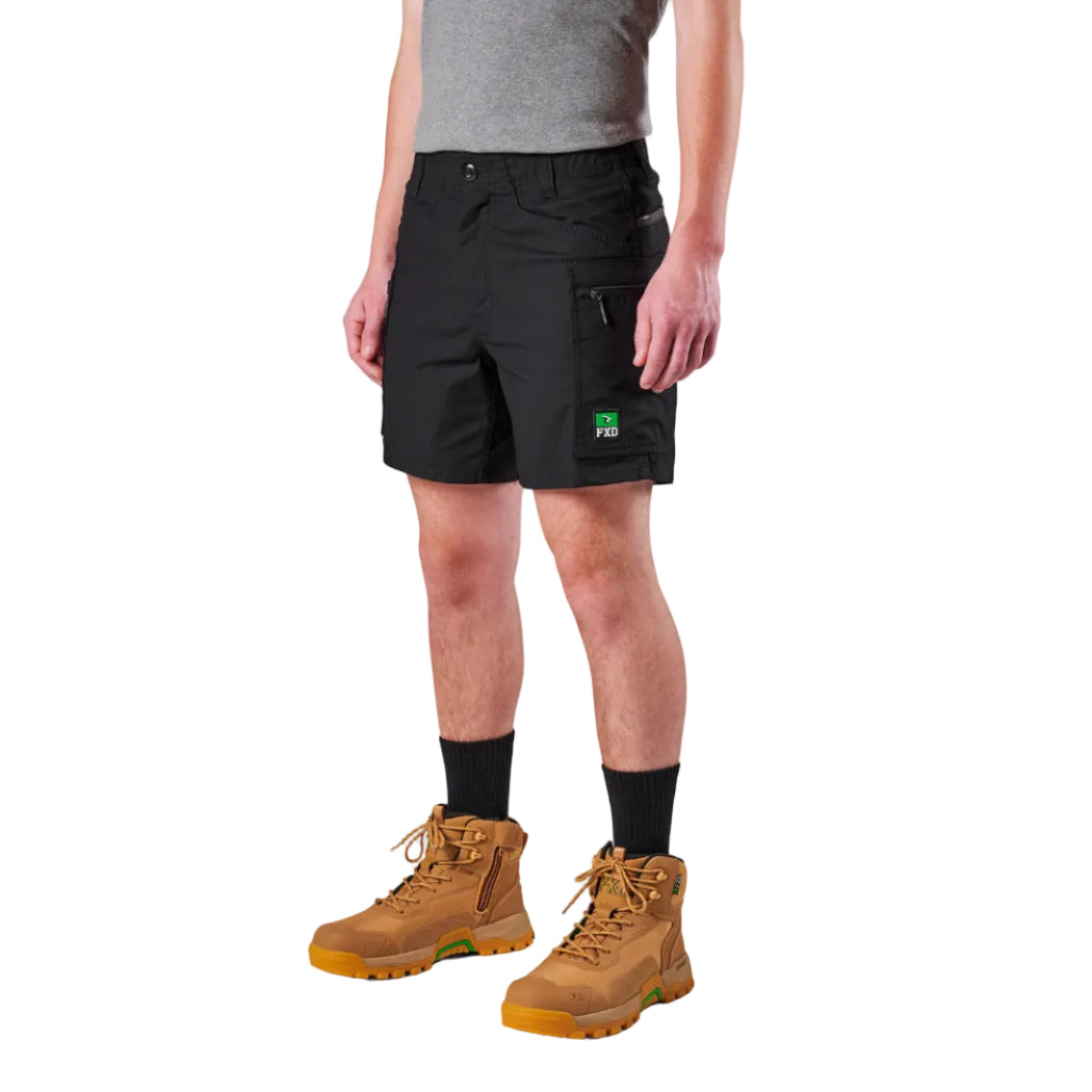 A model from the waist down wearing black FXD Men's WS-6 Work Shorts (FX02306021), black crew socks, and tan work boots against a plain white background.