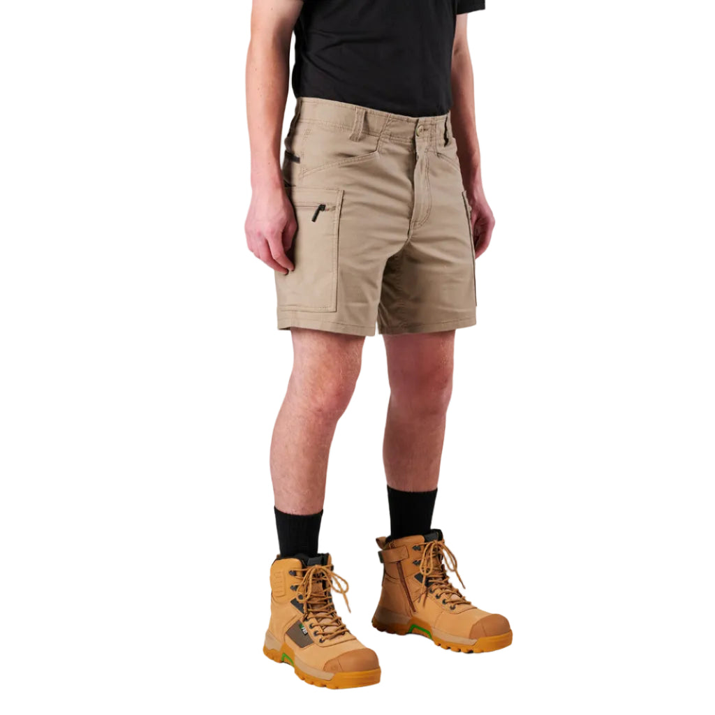 A model from the waist down wearing khaki FXD Men's WS-6 Work Shorts (FX02306021), a black tee, black crew socks, and tan work boots against a plain white background.
