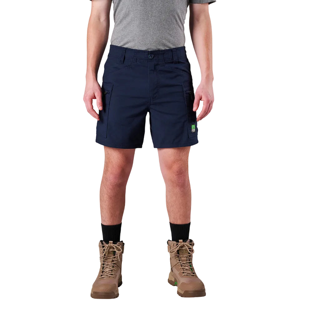 A model from the waist down wearing navy FXD Men's WS-6 Work Shorts (FX02306021), a grey tee, black crew socks, and tan work boots against a plain white background.