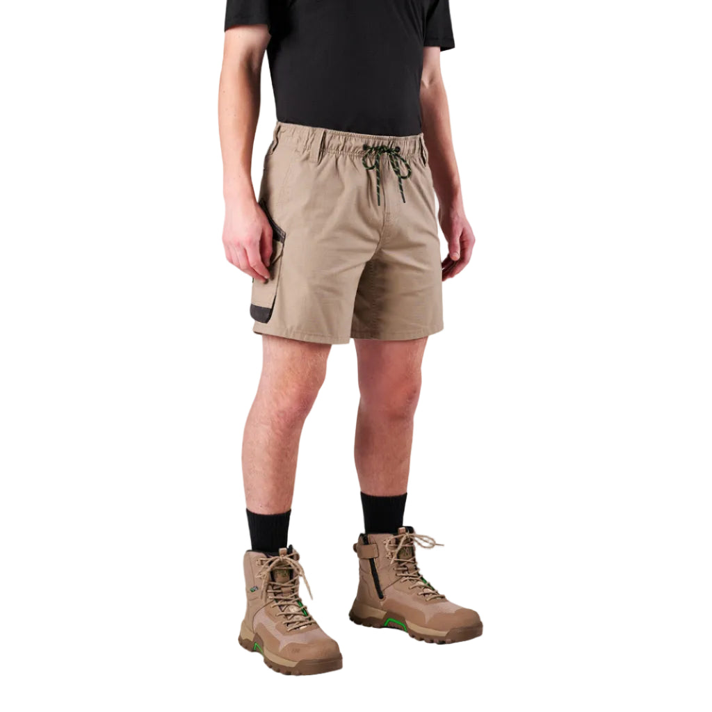 A man modelling khaki FXD Men's WS-7 Work Shorts (FX02306022) with a black tee, black crew socks and stone coloured boots on a white background.