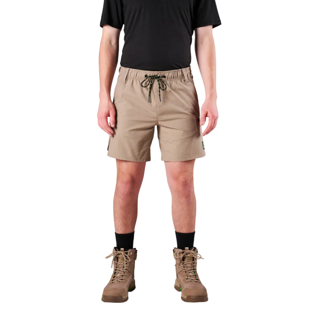A man modelling khaki FXD Men's WS-7 Work Shorts (FX02306022) with a black tee, black crew socks and stone coloured boots on a white background.