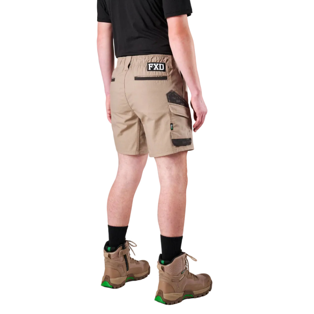 A man modelling khaki FXD Men's WS-7 Work Shorts (FX02306022) with a black tee, black crew socks and stone coloured boots on a white background.