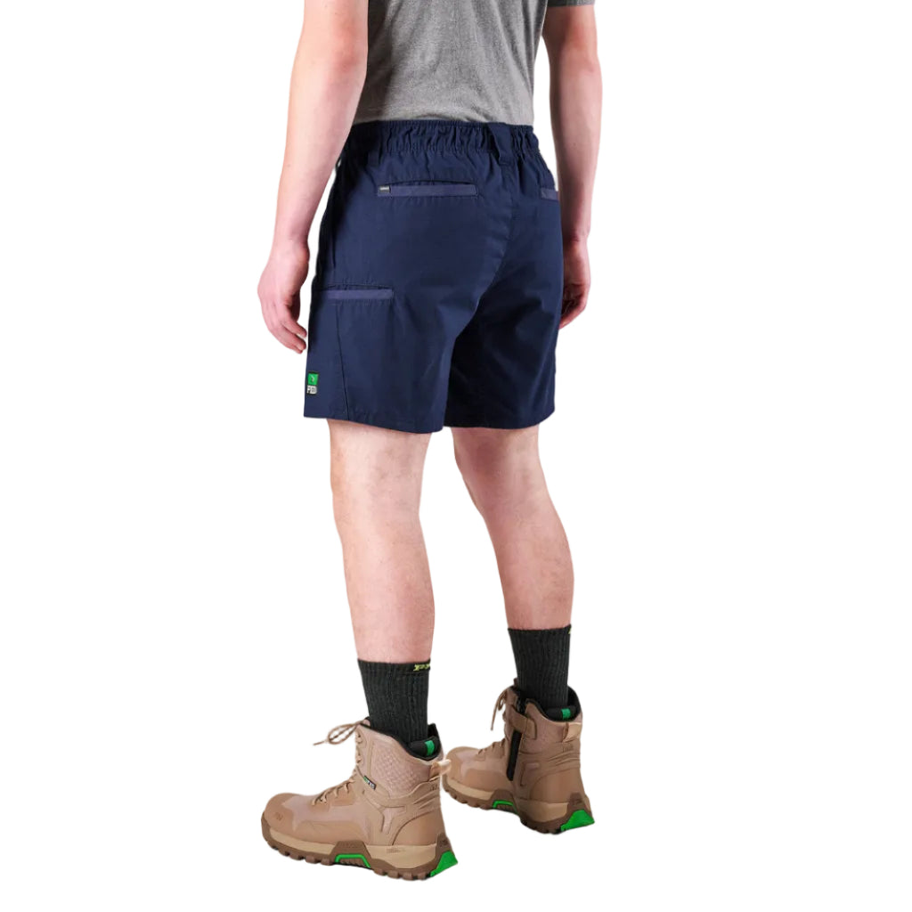 A man modelling navy FXD Men's WS-7 Work Shorts (FX02306022) with a grey tee, black crew socks and stone coloured boots on a white background.