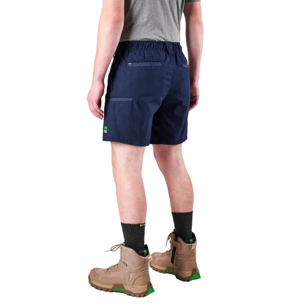 A man modelling navy FXD Men's WS-7 Work Shorts (FX02306022) with a grey tee, black crew socks and stone coloured boots on a white background.