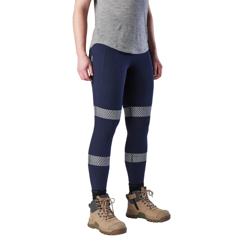 A woman wearing a pair of navy FXD Women's Taped Work Leggings (WP-9WT) paired with a grey tee and stone coloured work boots.