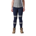 A woman wearing a pair of navy FXD Women's Taped Work Leggings (WP-9WT) paired with a grey tee and stone coloured work boots.