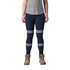 A woman wearing a pair of navy FXD Women's Taped Work Leggings (WP-9WT) paired with a grey tee and stone coloured work boots.