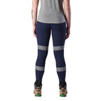 A back view of a woman wearing a pair of navy FXD Women's Taped Work Leggings (WP-9WT) paired with a grey tee and stone coloured work boots.