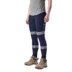 A woman wearing a pair of navy FXD Women's Taped Work Leggings (WP-9WT) paired with a grey tee and stone coloured work boots.