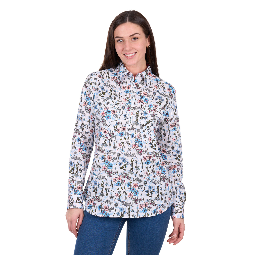 A woman with long brown hair, wearing the Hard Slog Womens Alice Half Button L/S Shirt (H6W2101174) in blue and blue jeans, smiles against a plain white background.