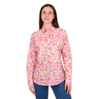 A woman with straight brown hair and a slight smile faces forward, wearing the Hard Slog Womens Samira Half Button L/S Shirt (H6W2101173) in pink/yellow floral print and blue jeans.