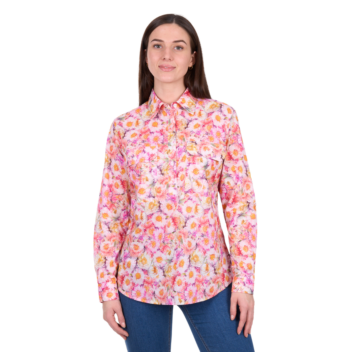 A woman with straight brown hair and a slight smile faces forward, wearing the Hard Slog Womens Samira Half Button L/S Shirt (H6W2101173) in pink/yellow floral print and blue jeans.