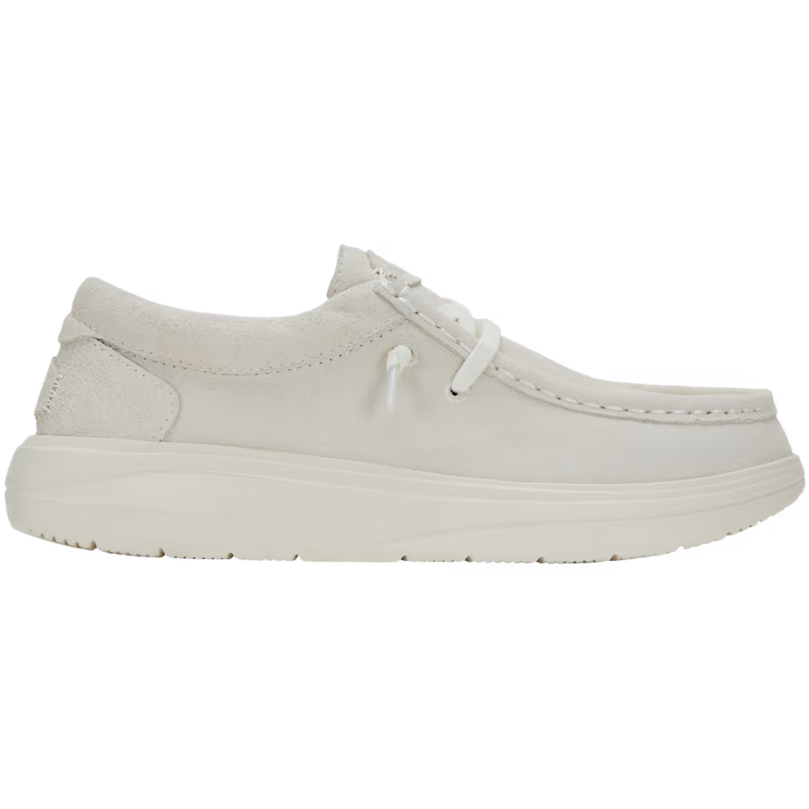 A side view of Hey Dude Womens Wendy Comfort Suede Slip On Shoes in ivory, featuring a thick sole, premium suede upper, moccasin-style stitching, and a low-cut design.