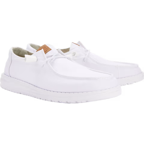 Hey Dude Womens Wendy Stretch Canvas Slip On Shoes (40902-100) in white by Hey Dude, featuring a washed canvas upper, textured lightweight outsole, stitched design, lace-up front, and a small brown tag near the tongue, shown on a plain white background.