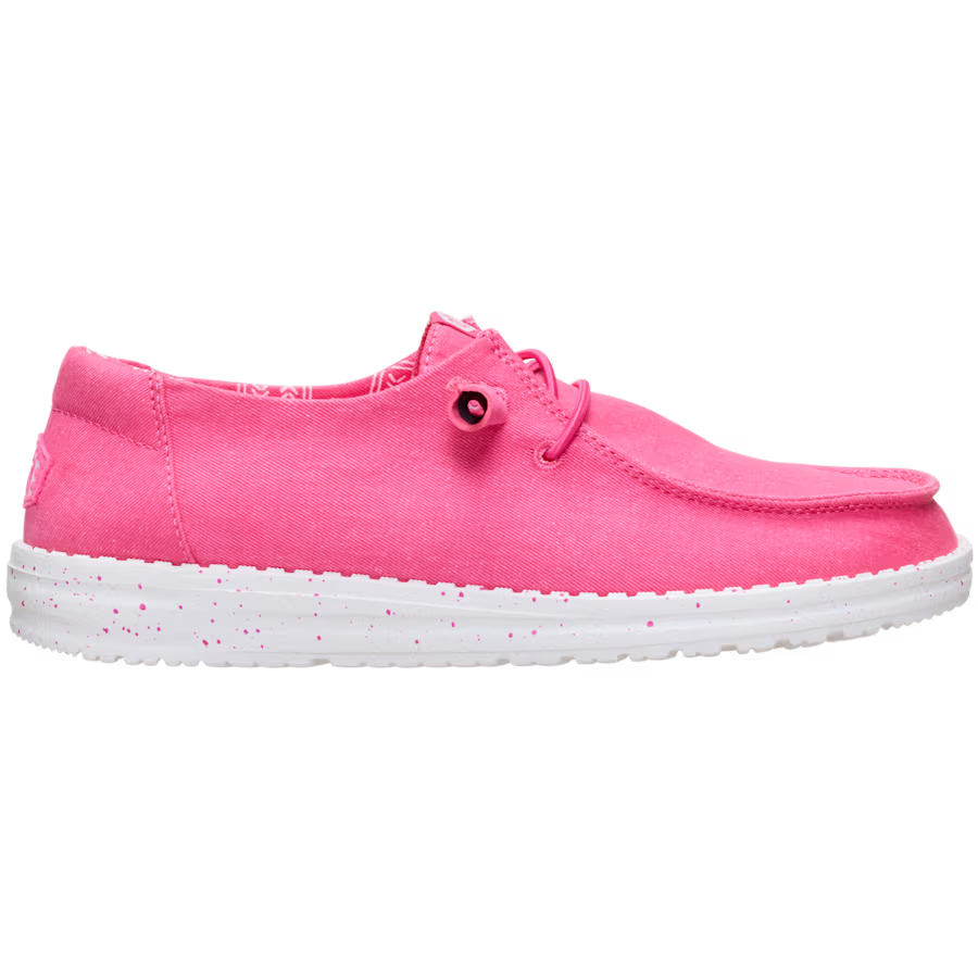 The Hey Dude Womens Wendy Stretch Canvas Slip On Shoes in Fandango Pink feature a bright pink washed canvas upper, white speckled sole, elastic laces, and low profile design, shown from the side against a plain white background.