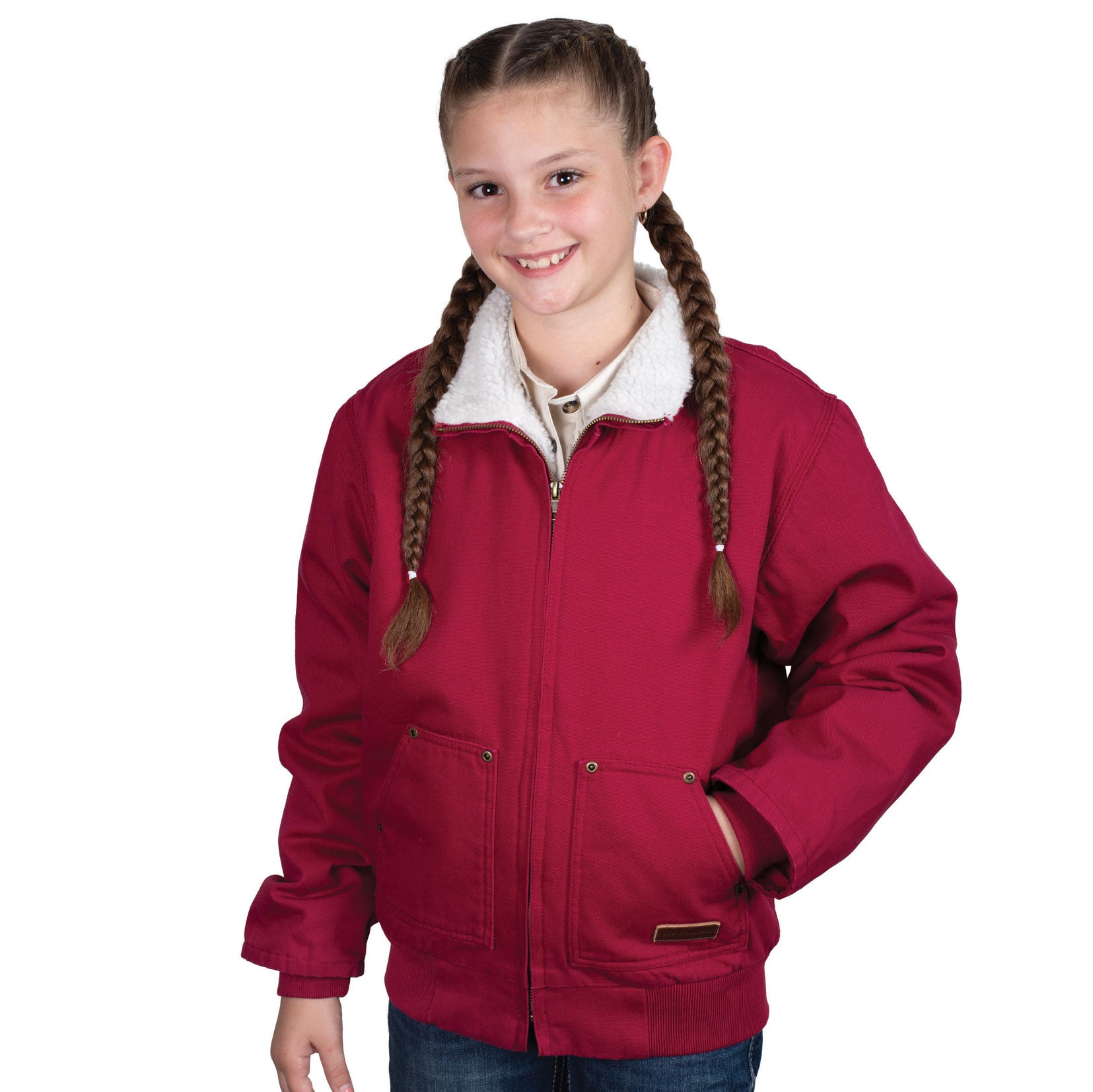 A smiling girl with braided hair wears the Just Country Childrens Diamantina Sherpa Jacket in Very Berry, featuring a white sherpa-lined collar and metal zips, paired with blue jeans against a plain white background.