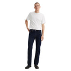 A man wearing dark blue rinse Levi's Men's 517 Heritage Bootcut Jeans (00517-0216), a white t-shirt, and black shoes, standing against a solid white background.