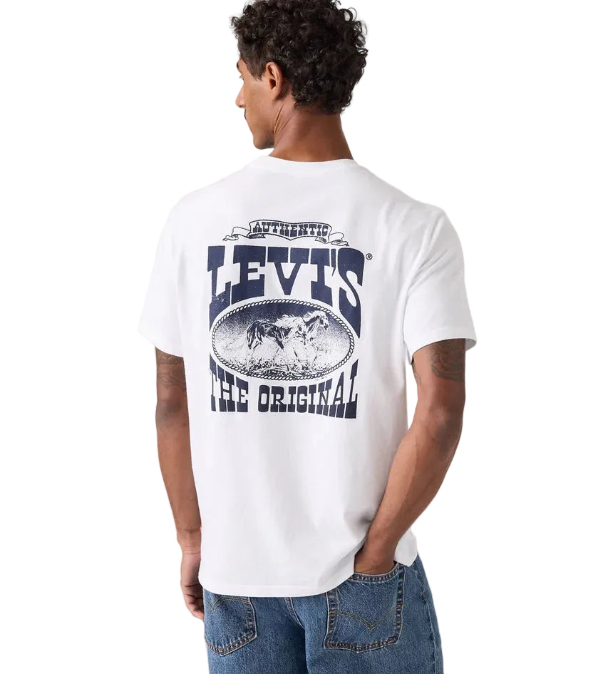 A man with short curly hair wears a Levi's Men's Graphic S/S Tee (16143-2384) Archival Cowboy 1 White—a relaxed fit, white tee with a large blue "LEVI'S THE ORIGINAL" graphic and oval image on the back—paired with blue jeans.