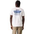 A man viewed from behind wearing a white Levi's t-shirt with a blue graphic print on the back, paired with khaki pants, against a white studio background.