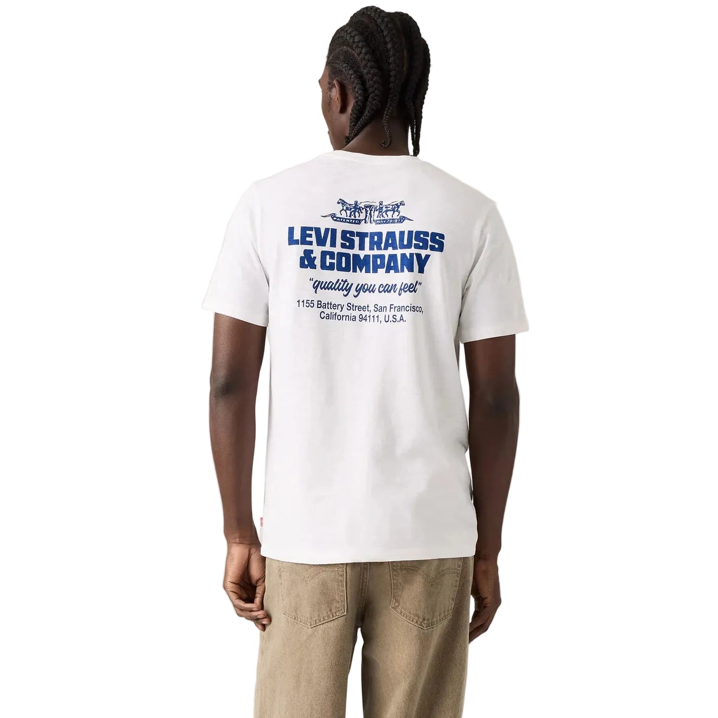 A man viewed from behind wearing a white Levi's t-shirt with a blue graphic print on the back, paired with khaki pants, against a white studio background.