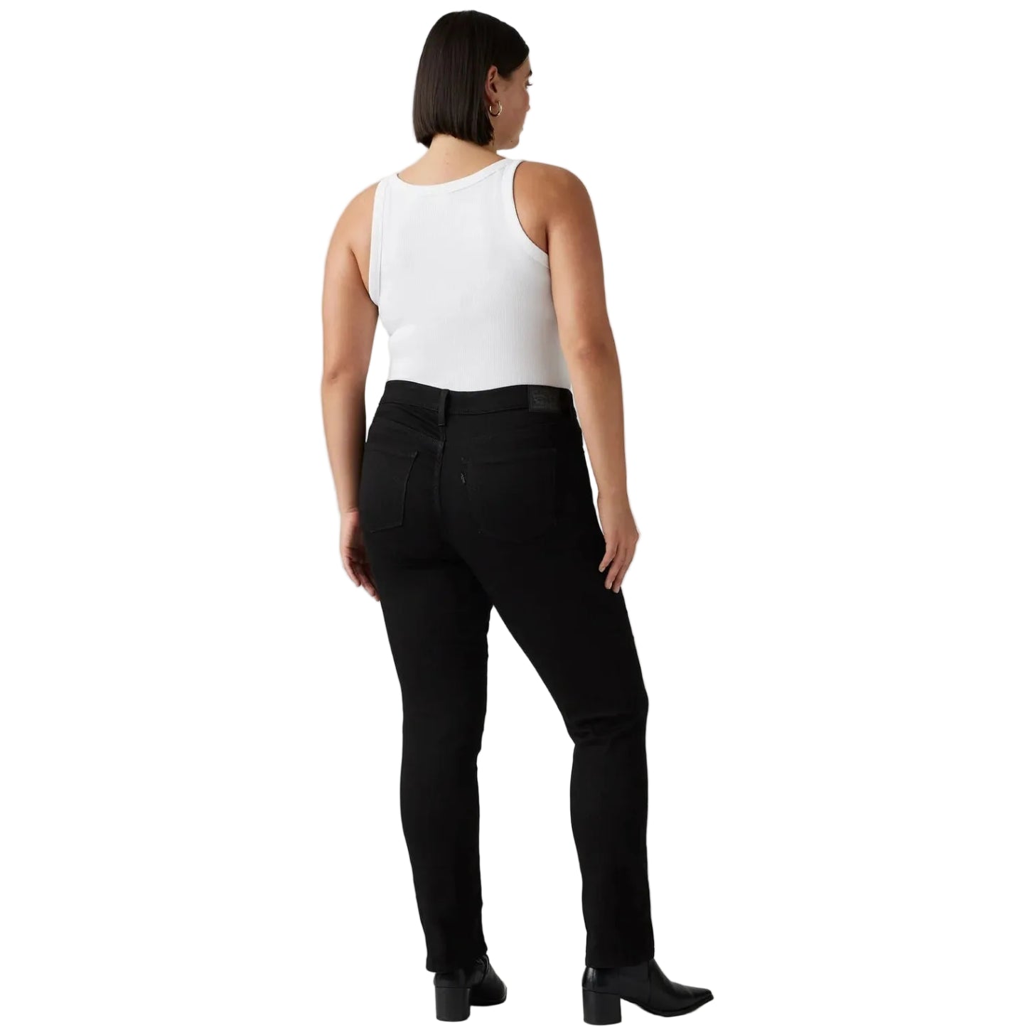 A woman shown from the back wearing black slim-fit jeans, a white sleeveless top, and black ankle boots against a white studio background.