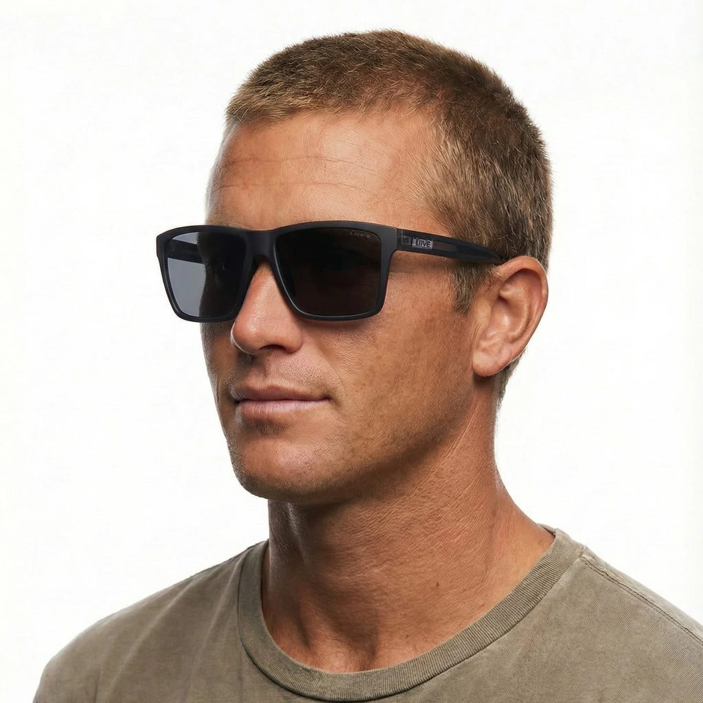 Headshot of a man modelling a pair of Liive Vision Bazza Sunglasses (L0670A) with matte black frames and smoke lenses, shown on a white background.