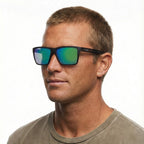 A headshot of a man modelling a pair of Liive Vision Bazza Sunglasses (L0671A) with a matte black frame and green mirrored lenses, shown against a plain white background.