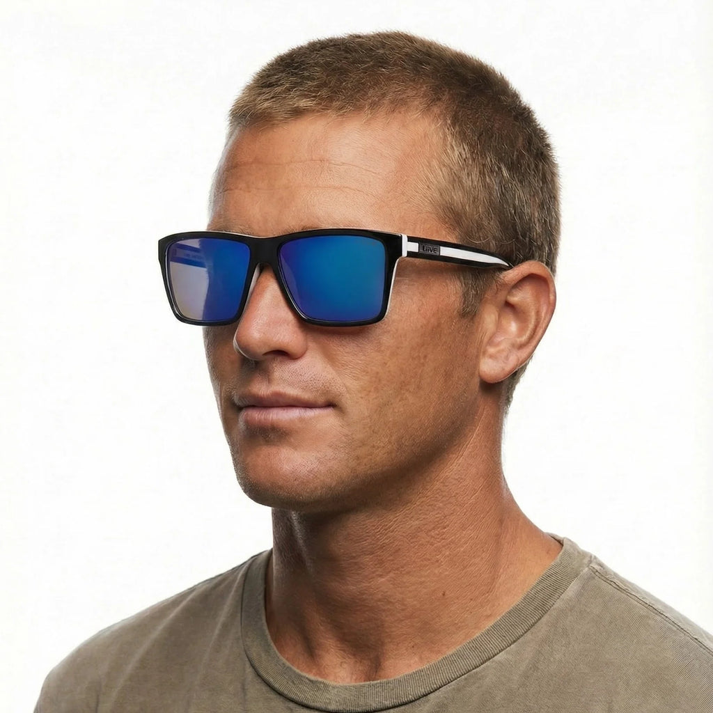 A headshot of a man modelling Liive Vision Laguna Sunglasses (L0717A) with matt black and white frames and vibrant blue mirrored lenses, shown against a plain white background.