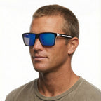 A headshot of a man modelling Liive Vision Laguna Sunglasses (L0717A) with matt black and white frames and vibrant blue mirrored lenses, shown against a plain white background.