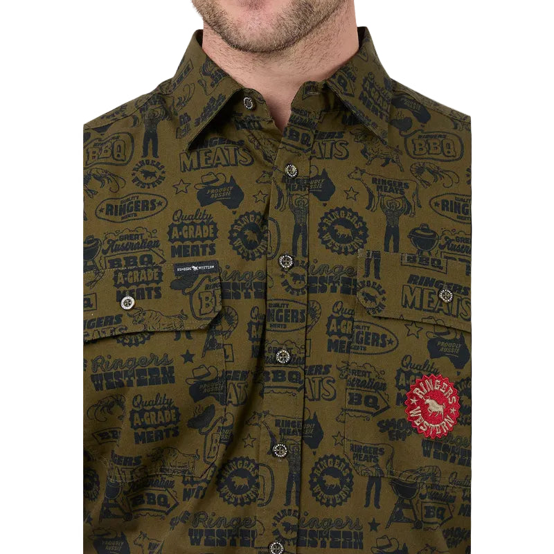 Close-up of a man wearing a button-down shirt with an all-over print. The shirt features a collar, snap buttons, chest pockets, and a red circular logo patch.