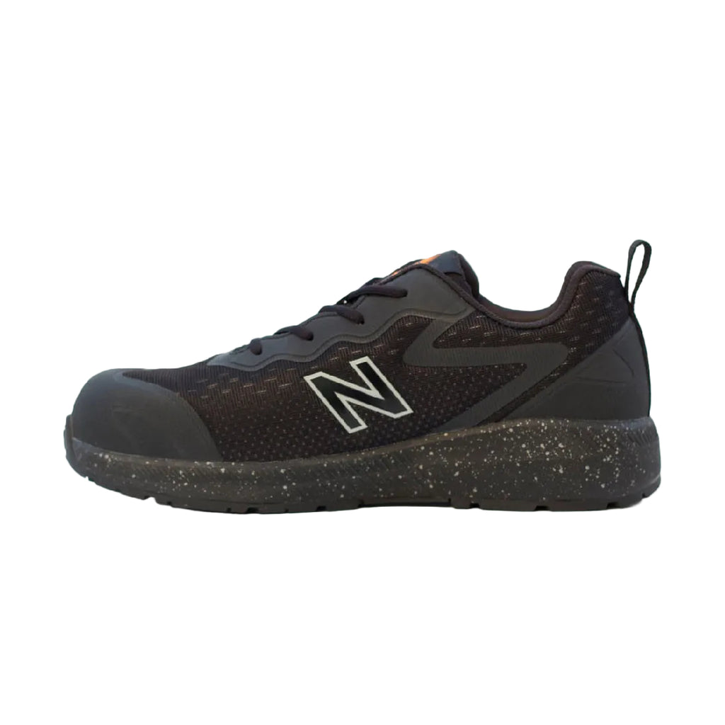 Side view of a black and orange New Balance Men's Logic Composite Toe Sneaker (MIDLOGI) with logo on the side, black laces, and a small orange accent near the tongue, shown against a plain white background.