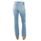 Rear view of a pair of light blue denim Pure Western High Rise Flora Bootcut Jeans (PCP2213725) with floral embroidery on the back pockets, worn by a model with brown heels against a white background.