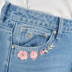 Close up of the front pocket detail of a pair of light blue denim Pure Western High Rise Flora Bootcut Jeans (PCP2213725) against a white background.